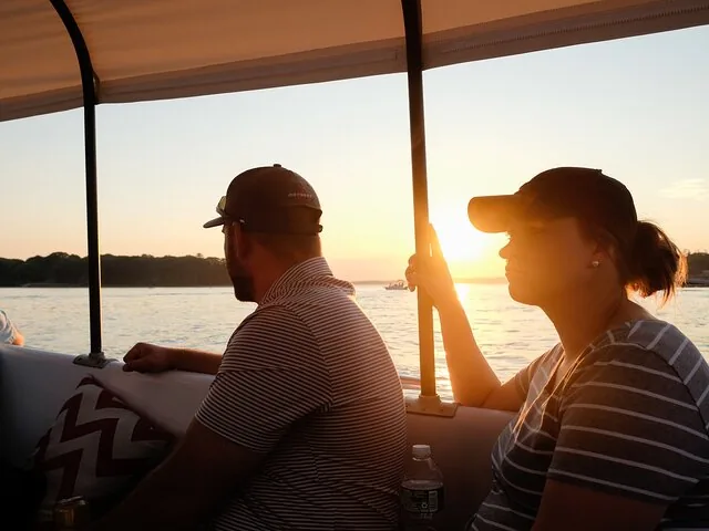 Twee mensen zitten op een boot en kijken uit over het water tijdens de zonsondergang.