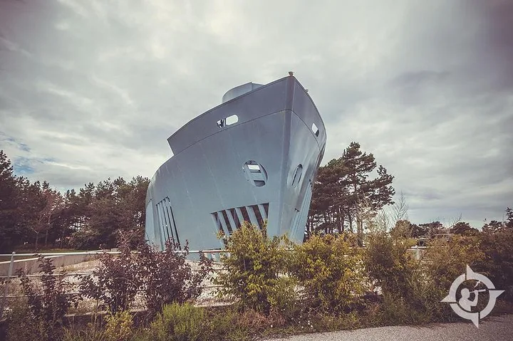 Ein großes graues Bauwerk, das dem Bug eines Schiffes ähnelt, steht an Land.